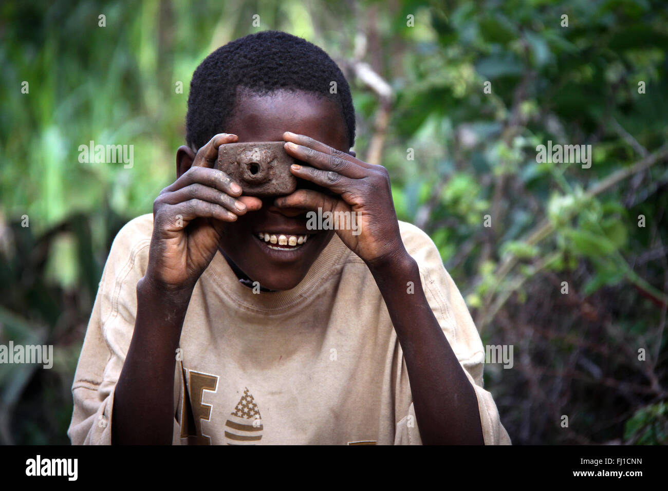 Bambino etiope giocando con una telecamera finta fatta di fango , nella foresta vicino Konso , Etiopia , Africa Foto Stock