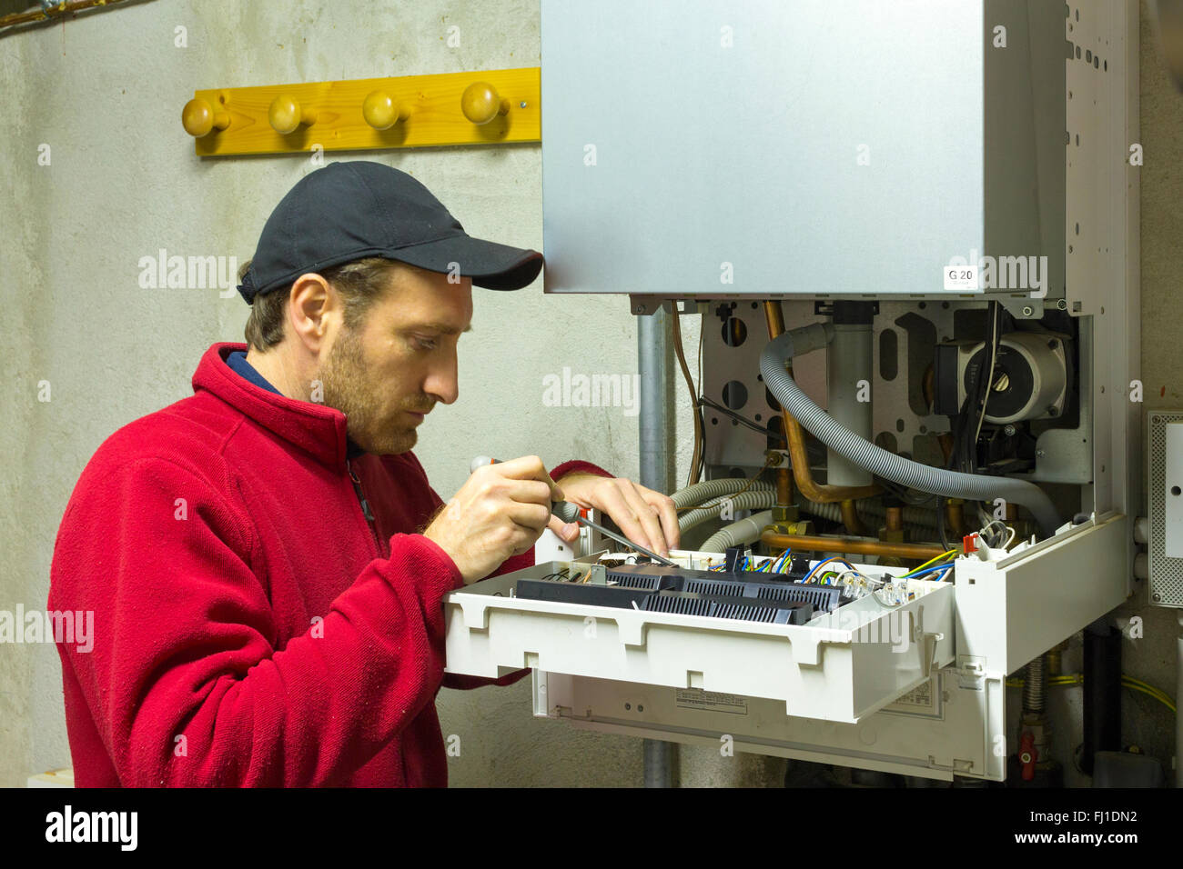 Plumber riparazione di una caldaia a condensazione nella sala caldaie Foto Stock