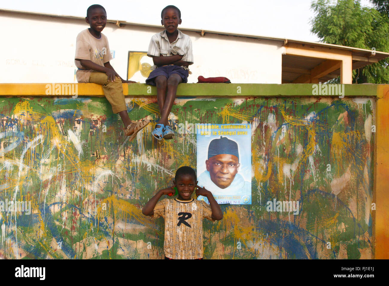 Ponendo i bambini per le strade di Tambacounda , Senegal , con poster del Presidente senegalese Abdoulaye Wade sulla parete Foto Stock