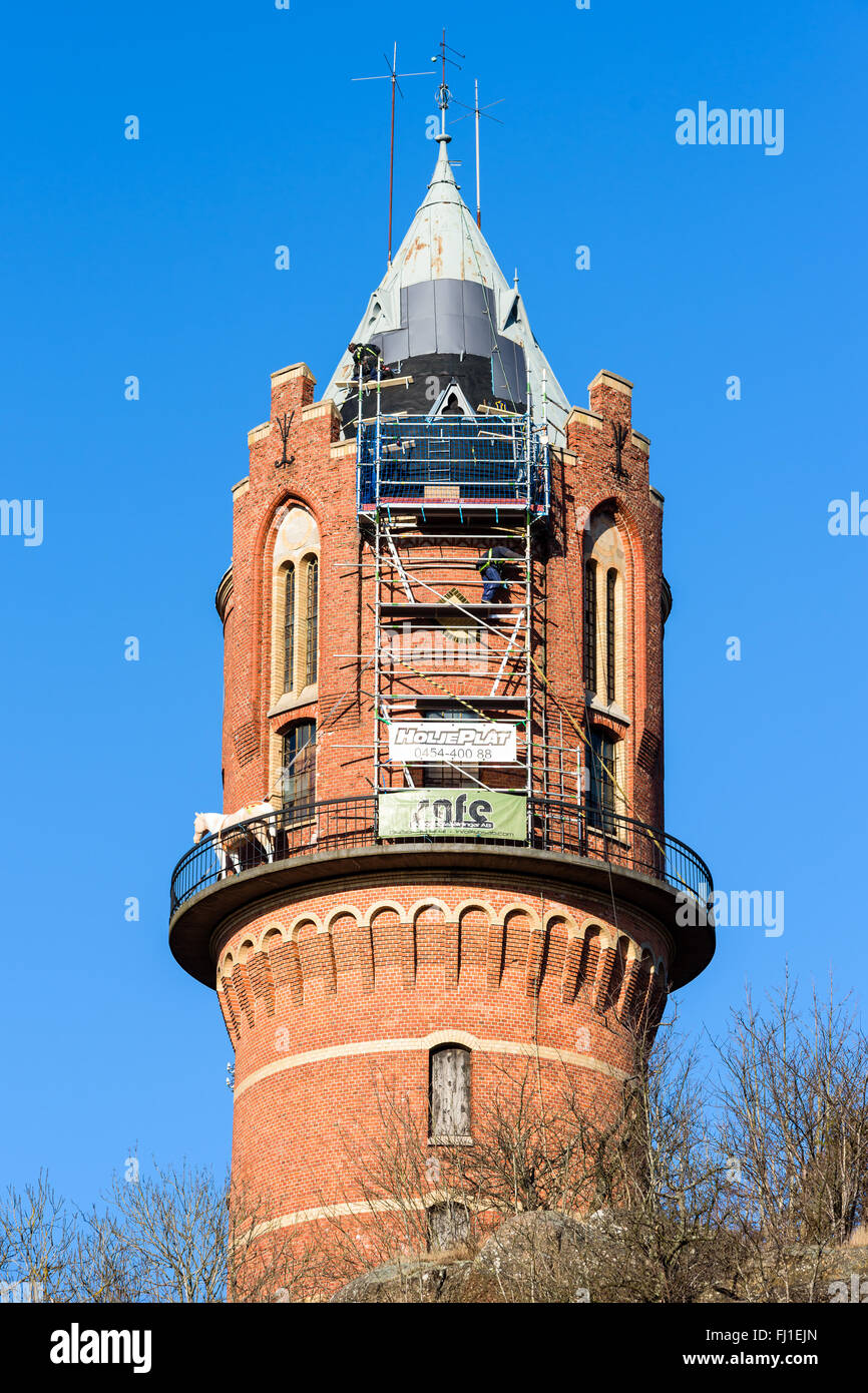 Ronneby, Svezia - 26 Febbraio 2016: alta altitudine riparazioni sul tetto della vecchia torre di acqua in città. Una persona è in v Foto Stock