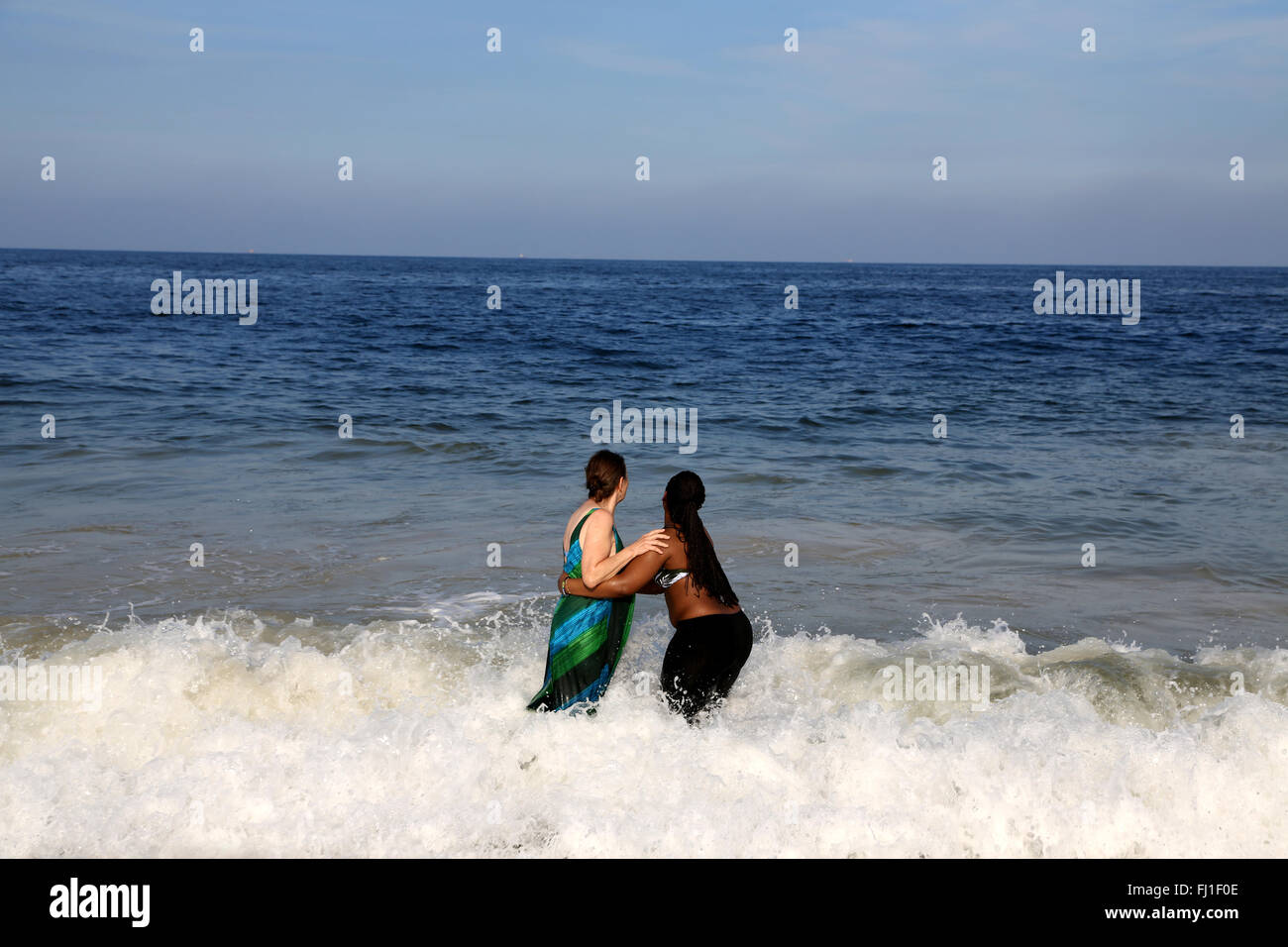 Bianco e nero donne azienda ogni altro sulla spiaggia di Ipanema, Brasile Foto Stock