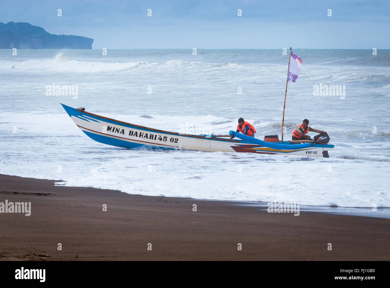 Yogyakarta, Indonesia - 18 Aprile 2010: due pescatori di portare la loro barca a riva di Parangtritis beach, Cetral Java, Indonesia. Foto Stock