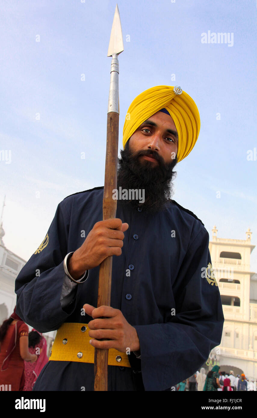 La religione Sikh l uomo con la lancia e lo zafferano turbante colorato nel tempio d'oro, Amritsar , India Foto Stock