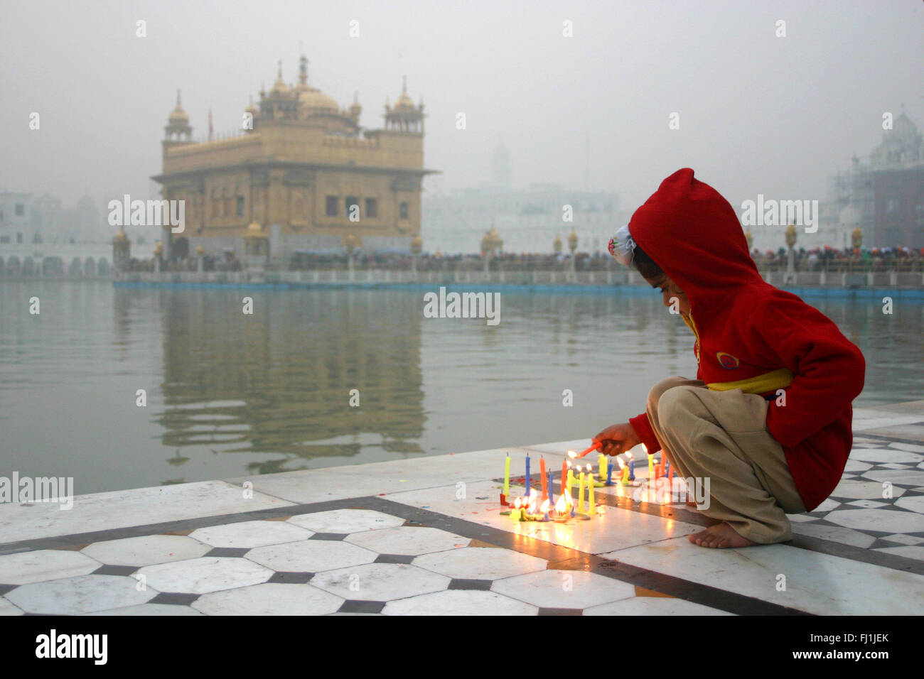 Bambino accendendo candele al tempio d'oro, Amritsar e India Foto Stock