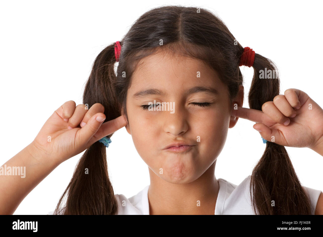 Bambina è di chiudere le sue orecchie con le dita su sfondo bianco Foto Stock