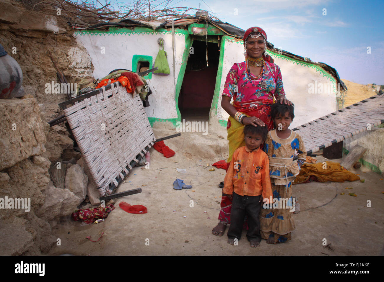 Una donna sta con i suoi bambini davanti alla loro casa in Jaisalmer , India Foto Stock