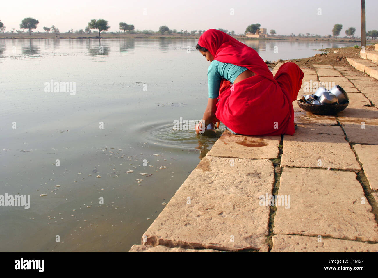 Donna lavaggio piatti in Gadi Sagar lago, Jaisalmer, India Foto Stock