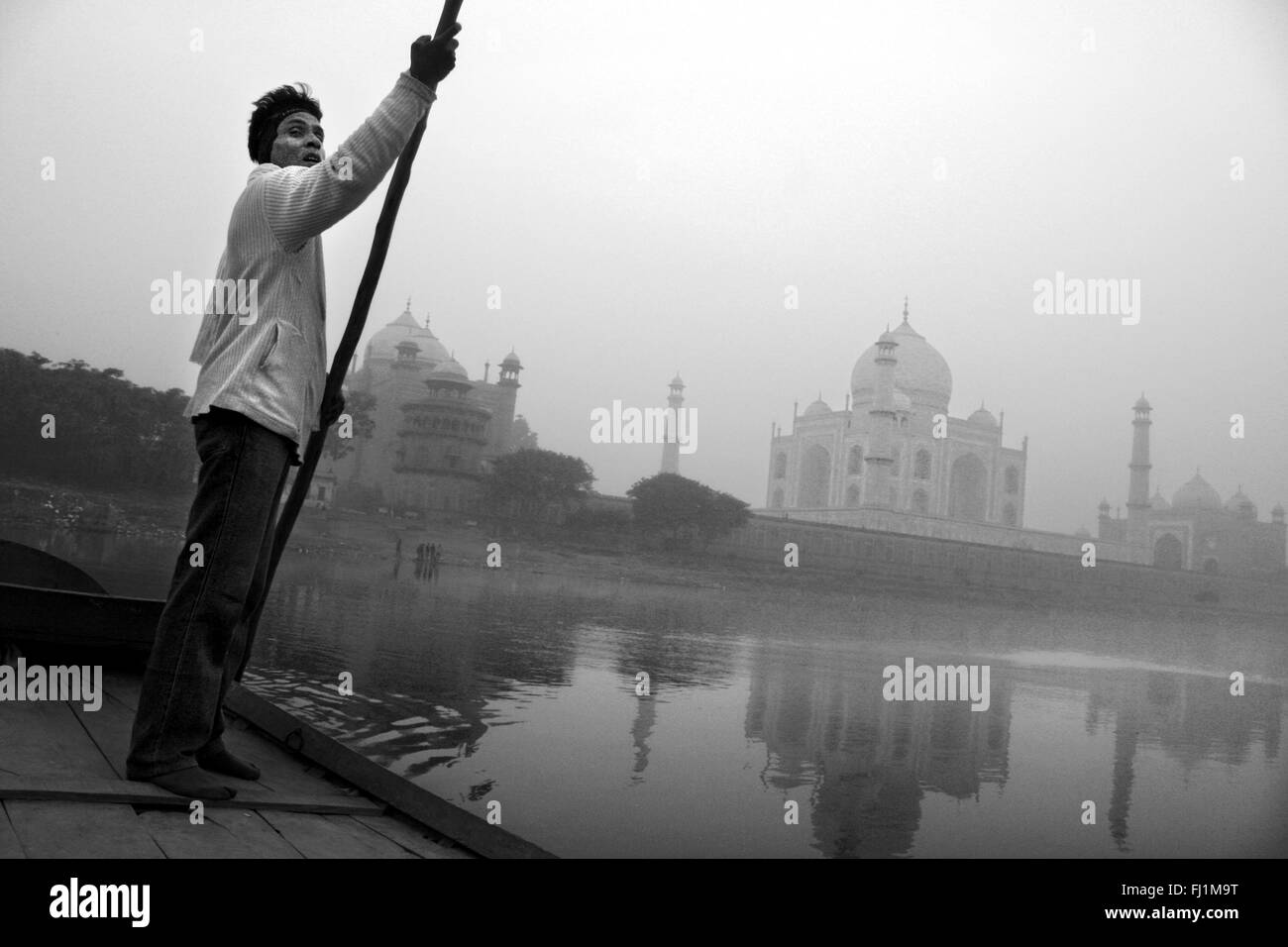 Uomo in barca sul fiume Yamuna, con Taj Mahal, nelle prime ore del mattino, Agra India Foto Stock