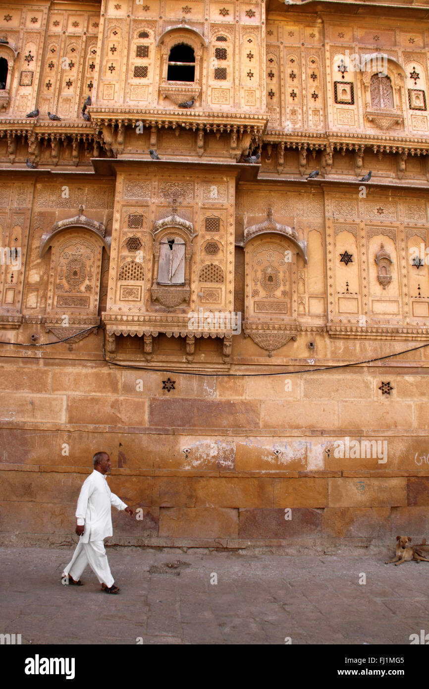 Uomo che cammina davanti a haveli in Jaisalmer , India Foto Stock