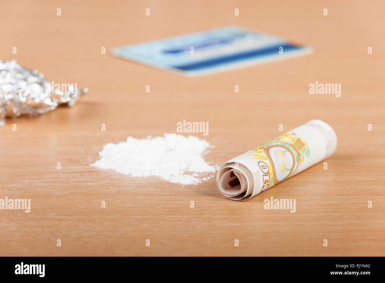 Pila di cocaina su un tavolo pronto per essere allineato con un arrotolato nota banca e una carta di credito Foto Stock