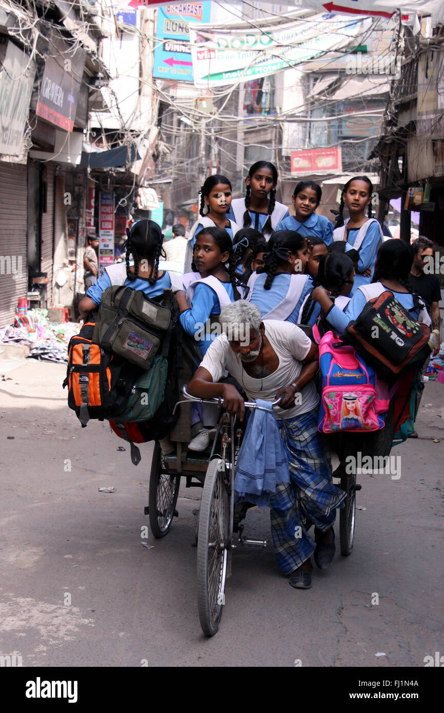 Uomo che lavora duramente per portare i bambini indiani a scuola al mattino a Delhi Foto Stock