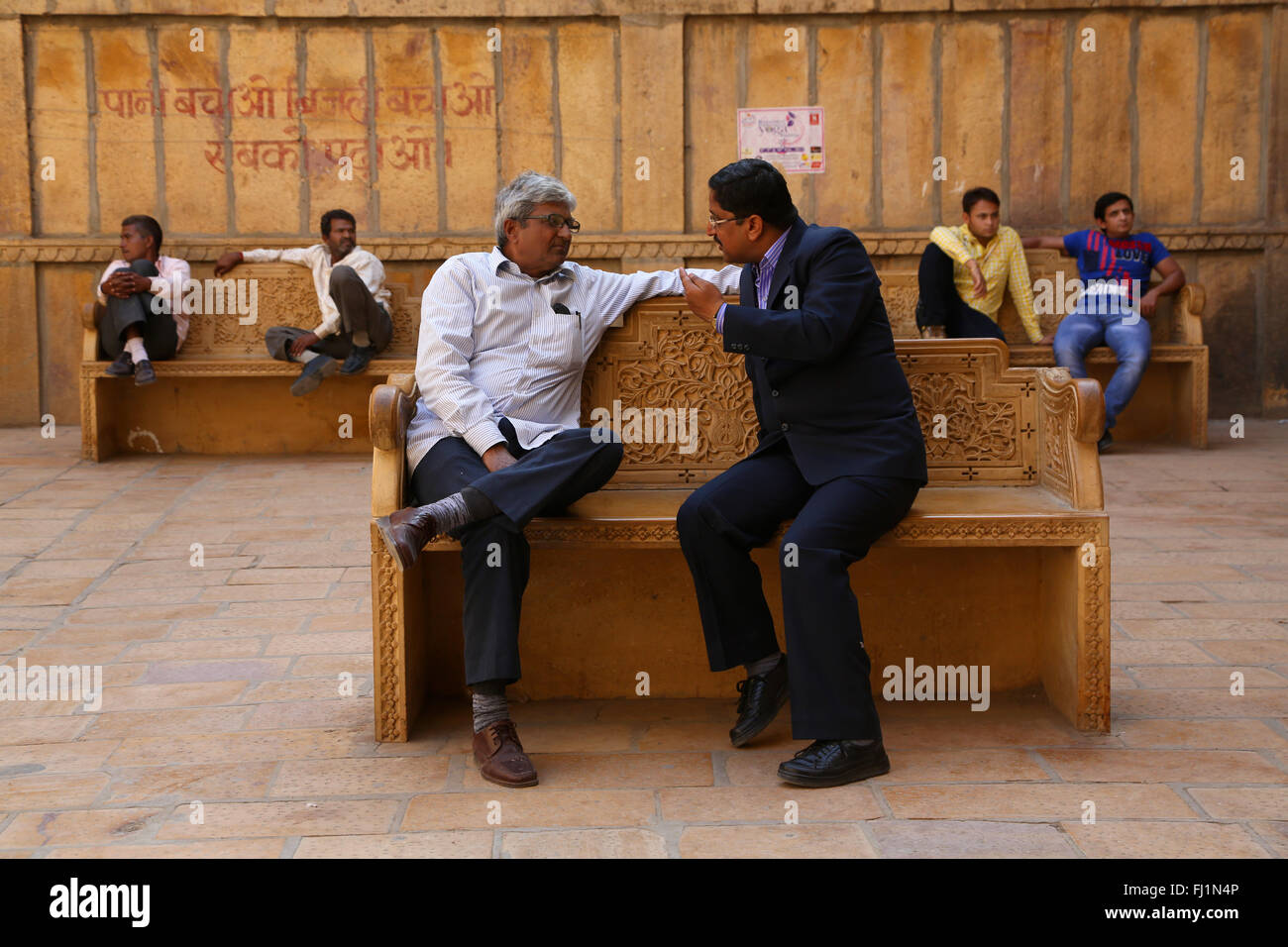 Due uomini stanno parlando su un banco in una strada a Jaisalmer , Rajasthan , India Foto Stock