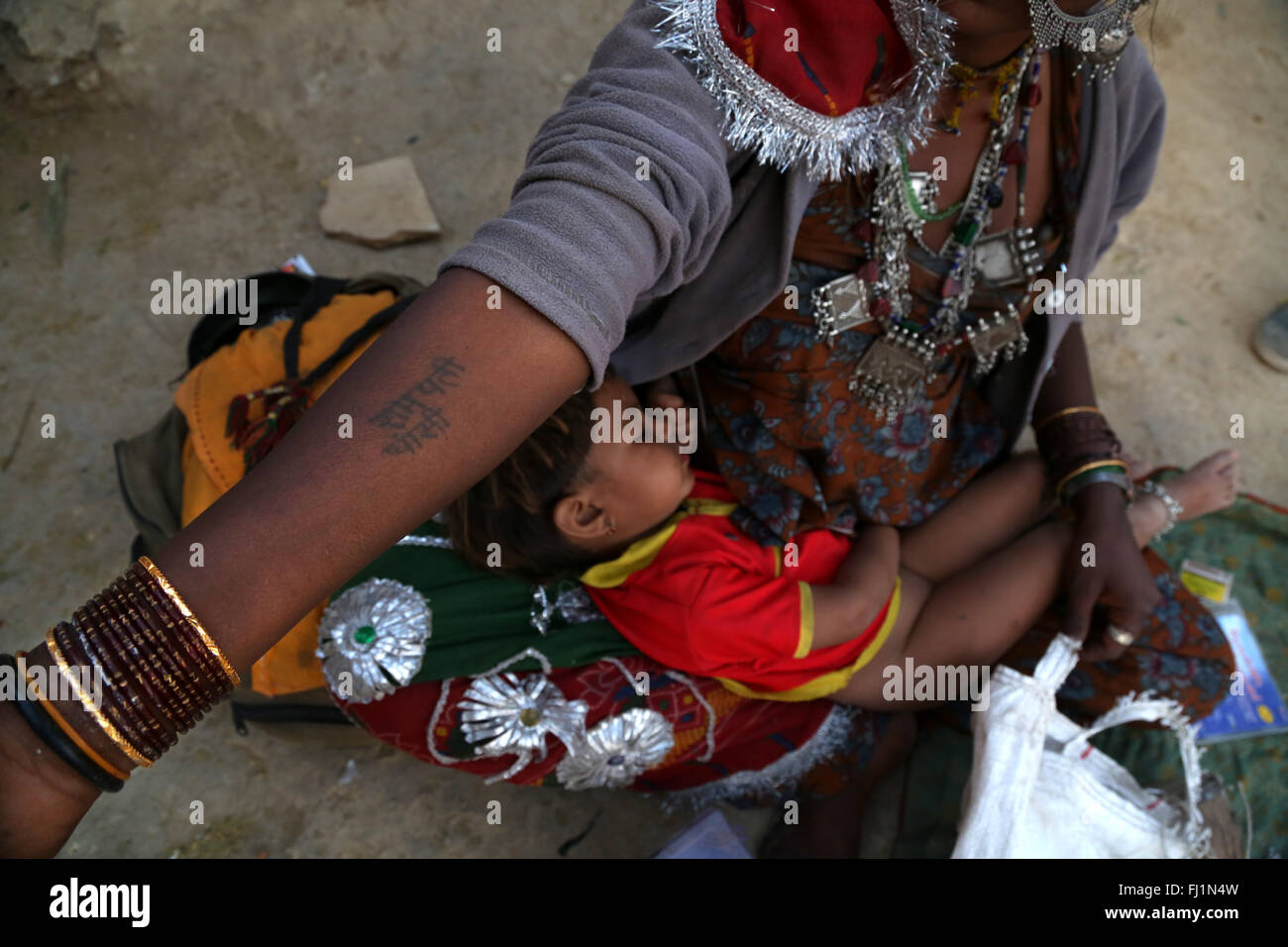 Una madre sta mostrando un tatuaggio sul suo braccio con la scrittura in lingua hindi mentre ella porta in sé il figlio in Jaisalmer , Rajasthan , India Foto Stock
