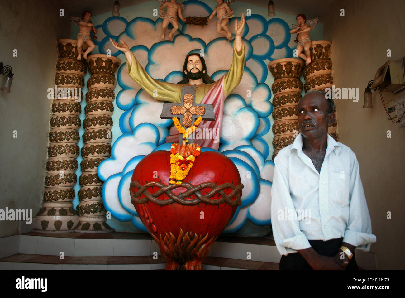 Indian Catholic uomo dentro la Nostra Signora dell Immacolata Concezione Chiesa witj colorato Gesù Cristo statua, Panjim , Goa Foto Stock