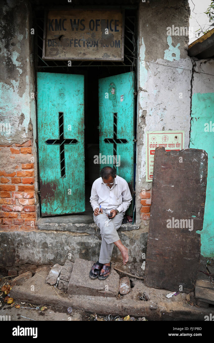 L'uomo della lettura in una strada di Kolkata con apri porta verde dietro hiù Foto Stock