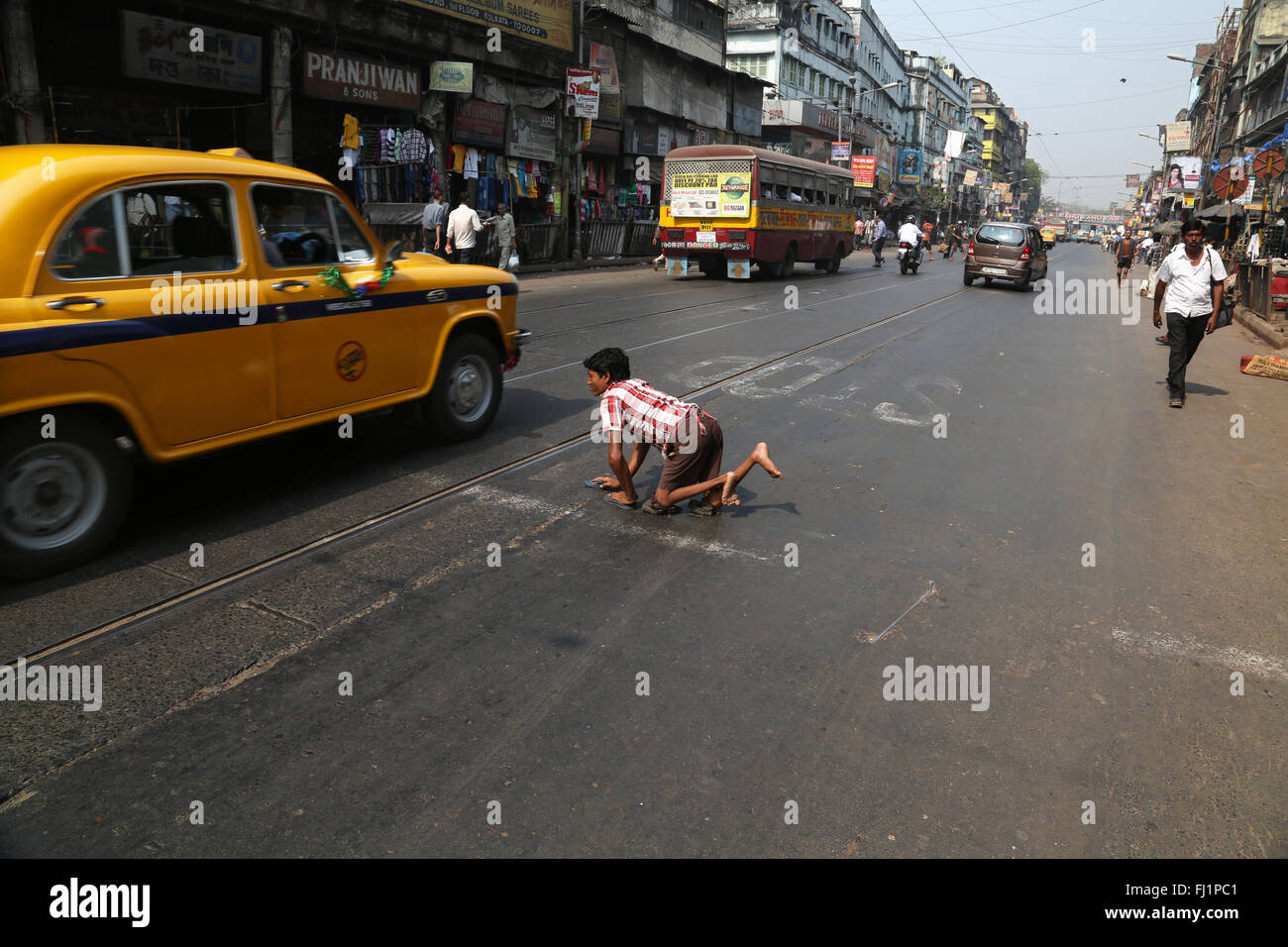 Disabilitato mendicante uomo attraversa una strada trafficata in Kolkata , India Foto Stock