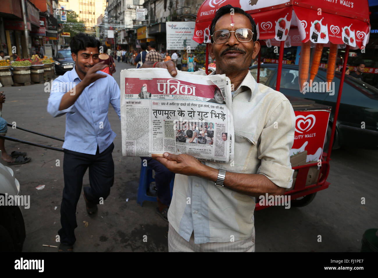 Uomo che mostra giornale con bengali iscritto in una strada di Calcutta , India Foto Stock