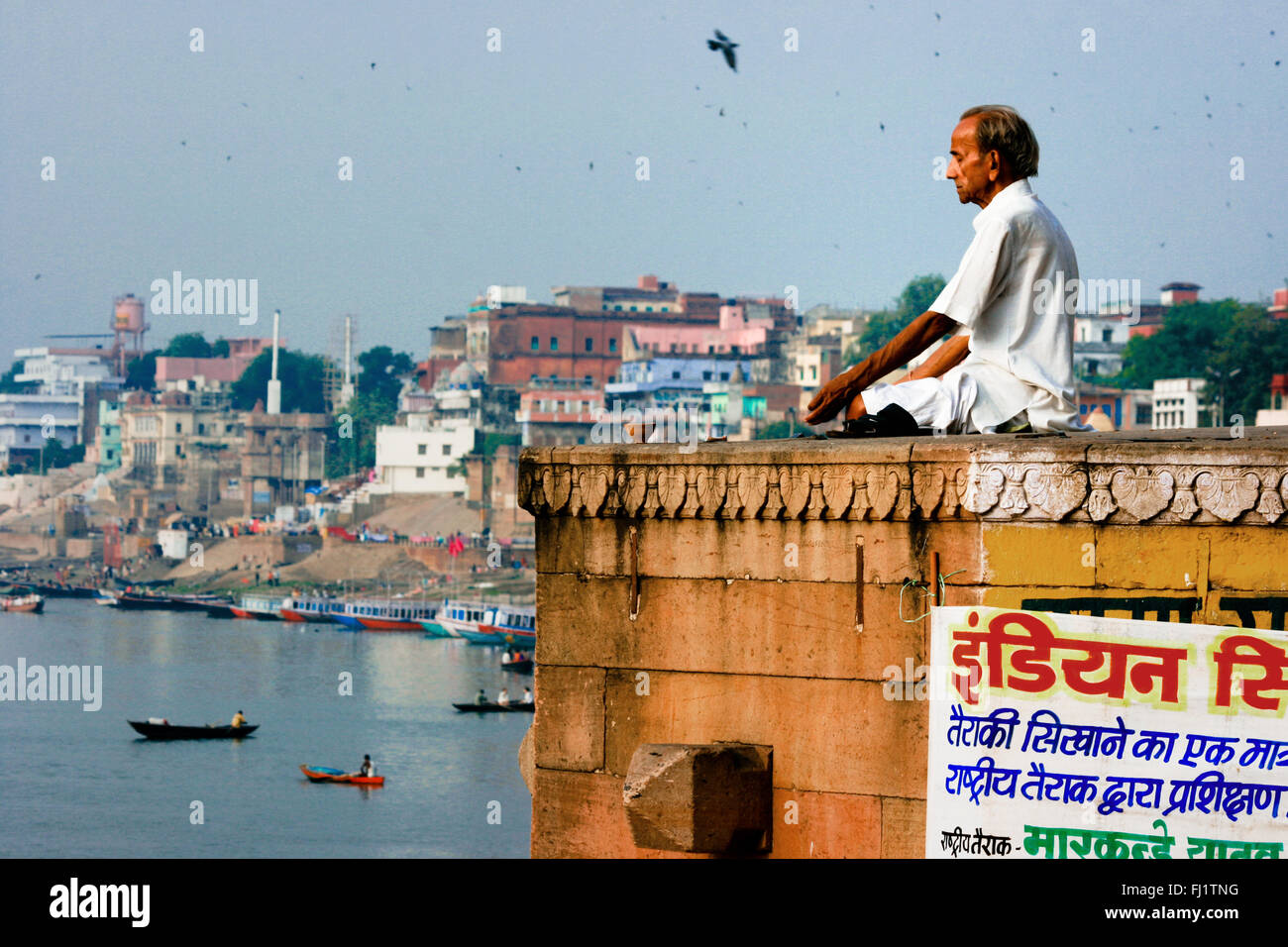 L'uomo facendo yoga meditazione su un ghat di Varanasi, India Foto Stock