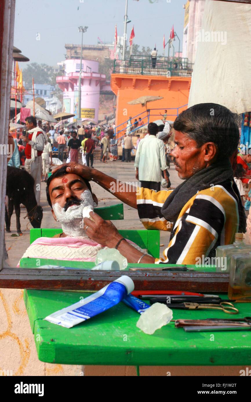 Barbiere di strada su un ghat di Varanasi, India Foto Stock