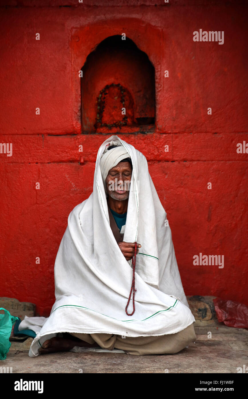 Yogi indù in preghiera con il rosario davanti a un tempio di Varanasi, India Foto Stock