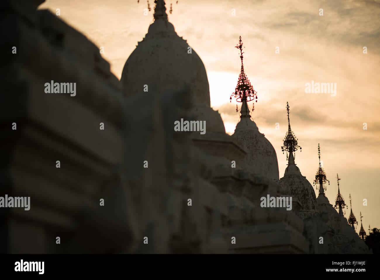 Kuthodaw Pagoda Hti Umbrella Spires Mandalay Myanmar // MANDALAY, Myanmar — piccole guglie decorative hti (ombrello) adornano il lato di uno stupa nella Pagoda di Kuthodaw. Questi elementi ornamentali sono caratteristiche tipiche della tradizionale architettura buddista birmana che si trova in tutto il complesso. La pagoda, costruita nel 1857 sotto il regno di re Mindon, ospita quello che è ampiamente conosciuto come il libro più grande del mondo - il canone buddista Pali completo inciso su 729 stele di marmo. Il complesso è stato iscritto nel Registro Mondiale della memoria dell'UNESCO nel 2013. La Pagoda di Kuthodaw continua a servire come buddhista attivo Foto Stock