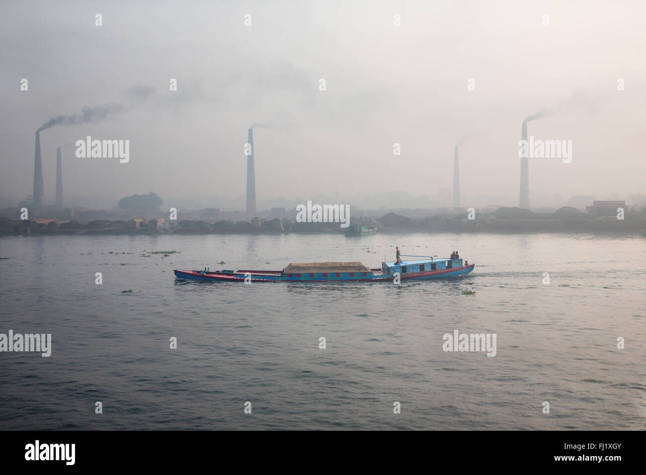 Fiume Buriganga vicino a Dhaka , Bangladesh , con fabbriche di mattoni sul retro Foto Stock