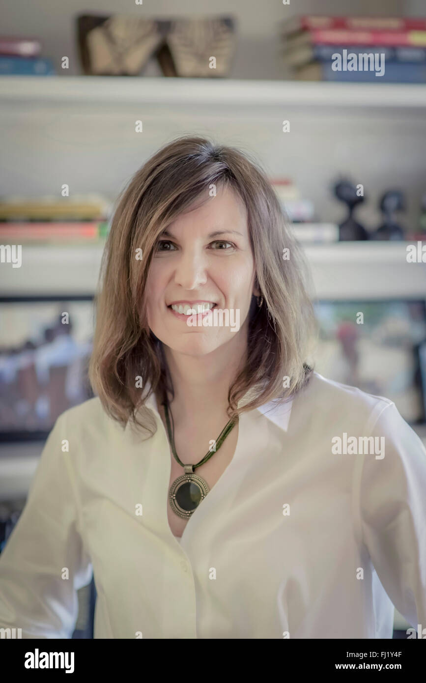 Donna in abiti aziendali, in piedi di fronte a un libro ripiano Foto Stock