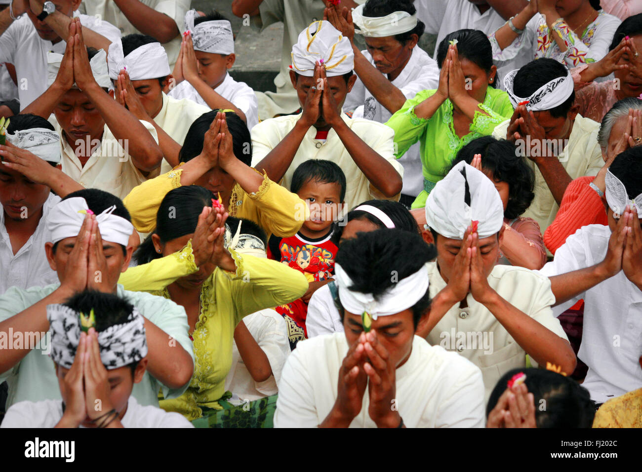 Bambino in una folla orante durante la celebrazione Kuningan, Ubud, Indonesia Foto Stock