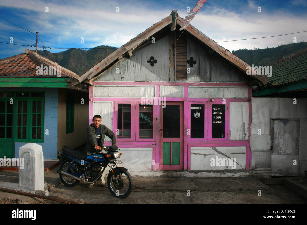 Uomo di fronte della tradizionale casa in legno in Cemoro Lawang village , Java , Indonesia Foto Stock