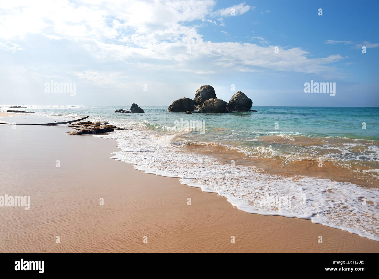 Mucchio di pietre in oceano vicino spiaggia sabbiosa Foto Stock