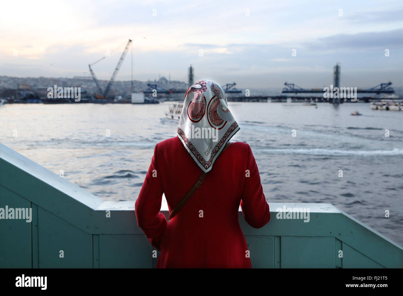 Un solitario donna guarda al fiume sul Bosforo dal Ponte Galata , Istanbul Foto Stock