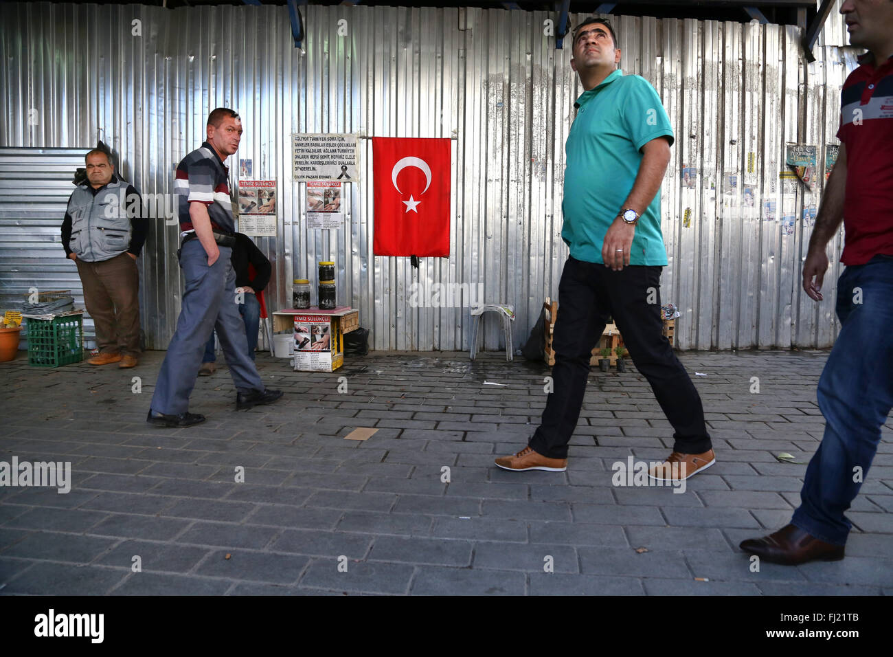 Gli uomini camminare per le strade di Istanbul con bagno turco bandiera nazionale sulla parete Foto Stock