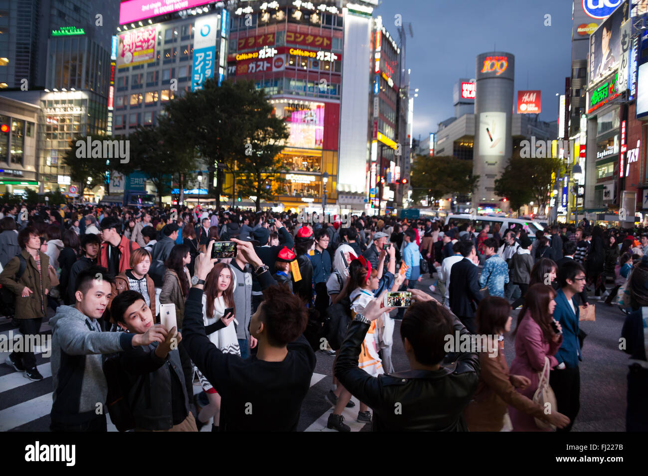 Due persone stanno prendendo selfie in mezzo alla folla all'incrocio di Shibuya, Tokyo Foto Stock