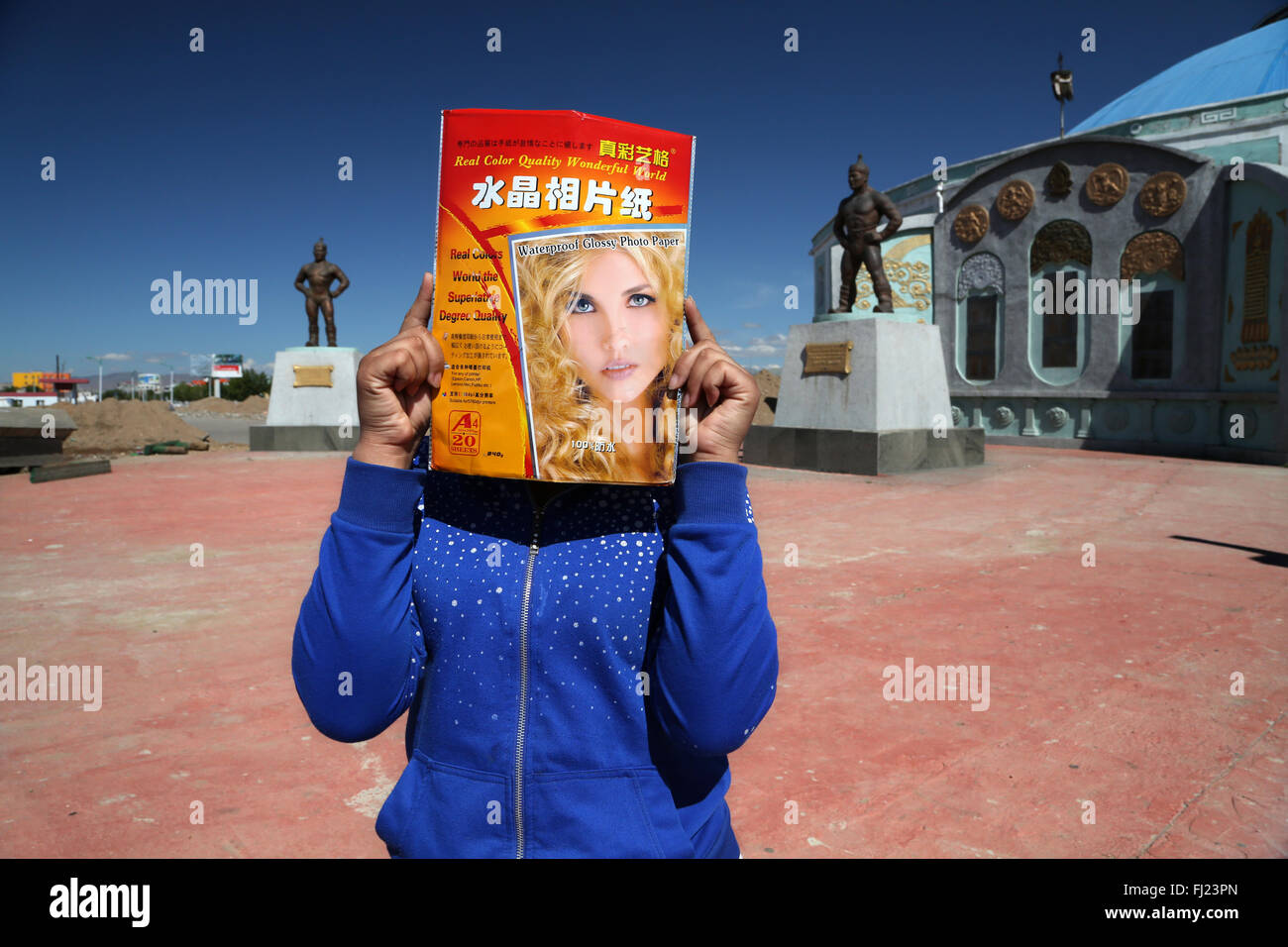 Donna mongola nasconde se stessa dietro una rivista cinese in città Mörön Foto Stock