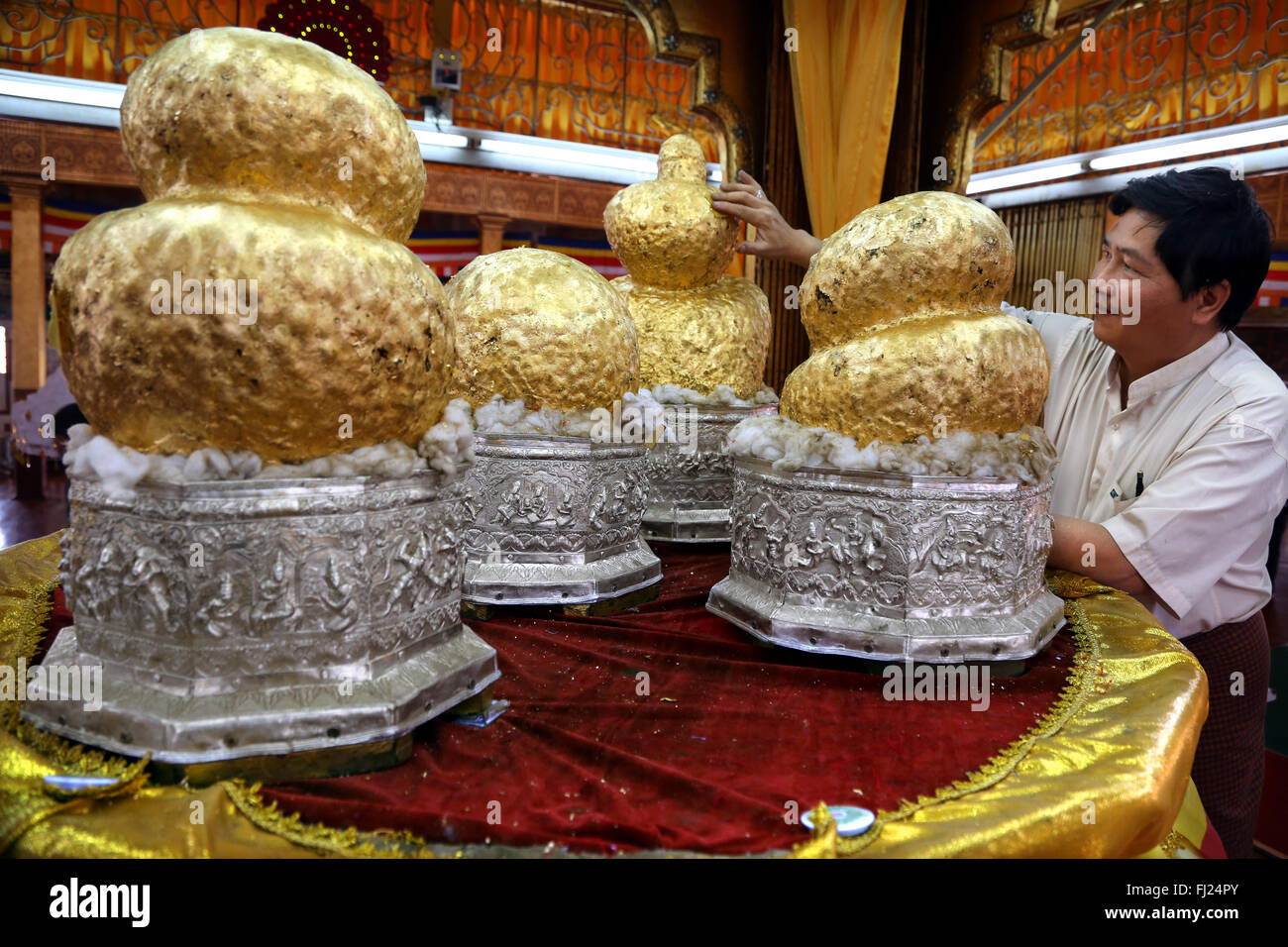 L uomo nel tempio sul Lago Inle mettendo goldleaves sulle statue di Buddha , Myanmar Foto Stock