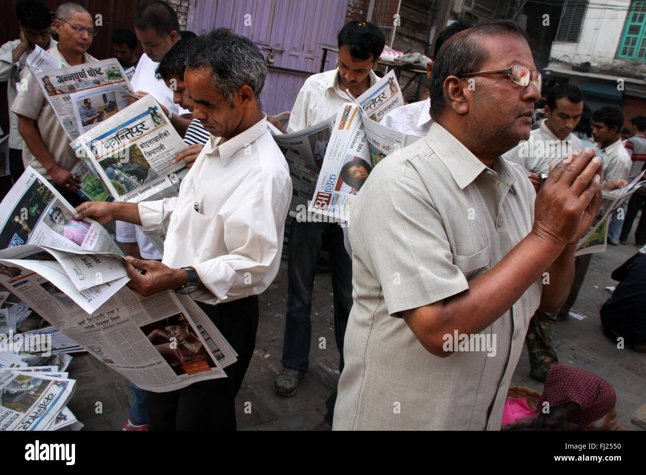 Persone che leggono i giornali per le strade di Kathmandu, Nepal Foto Stock