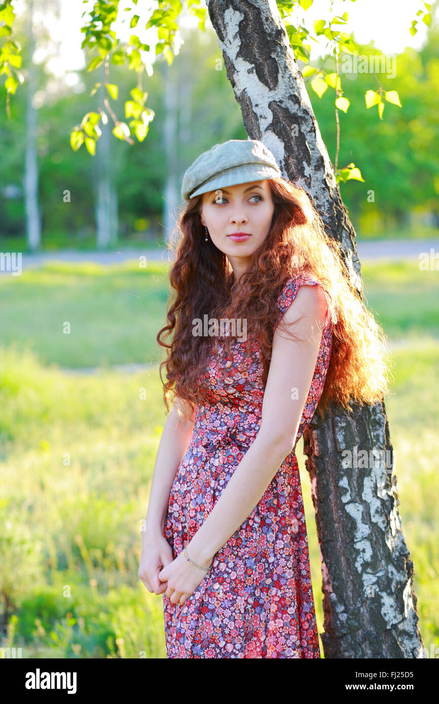 Redhead bella ragazza in un cappuccio in piedi vicino a tree Foto Stock