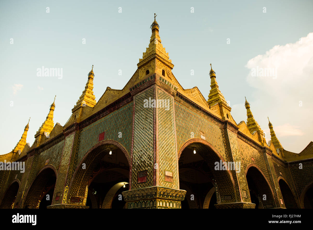 Sutaungpyei Pagoda Mosaic Exterior Mandalay Myanmar // MANDALAY, Myanmar — l'esterno decorato della Pagoda di Sutaungpyei (conosciuta anche come su Taung Pyae Pagoda) mostra intricati mosaici caratteristici della tradizionale architettura buddista del Myanmar. La pagoda si trova sulla sommità della collina di Mandalay, costruita durante il regno di re Mindon a metà del XIX secolo come parte della sua istituzione di Mandalay come capitale reale nel 1857. La struttura presenta imponenti pareti a mosaico specchiato che creano effetti visivi sorprendenti attraverso il riflesso della luce, a dimostrazione dell'eccezionale maestria artigianale di M. Foto Stock