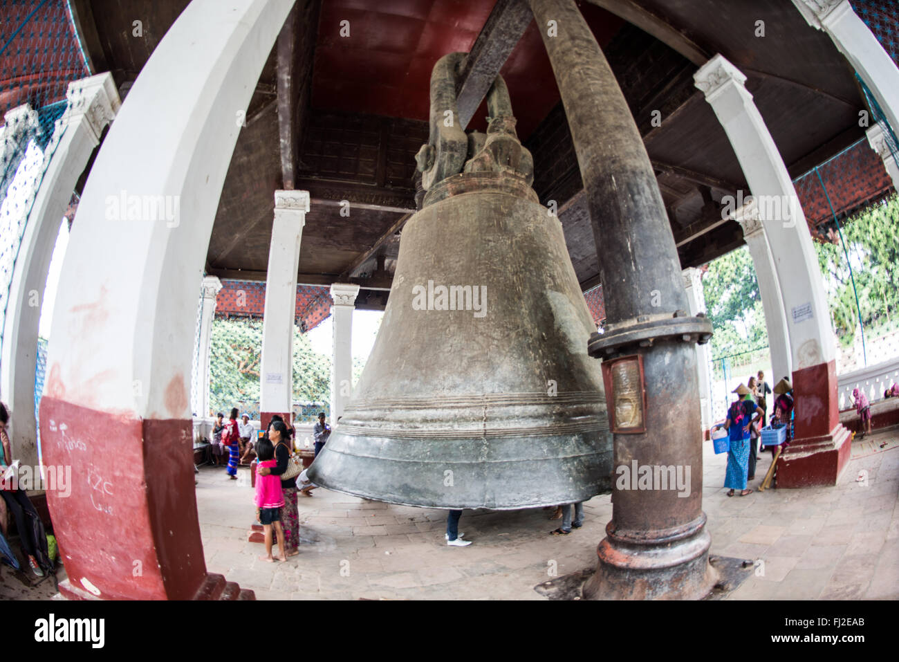 MINGUN, Myanmar - l'imponente campana di Mingun è appesa nel suo padiglione vicino a Mingun, Myanmar. Realizzata nel 1808 e con un peso di 90 tonnellate, è la campana che suona più grande del mondo. I visitatori si trovano sotto l'enorme campana di bronzo, che si erge su di loro a un'altezza di 3 metri e di 16 metri di diametro. Foto Stock