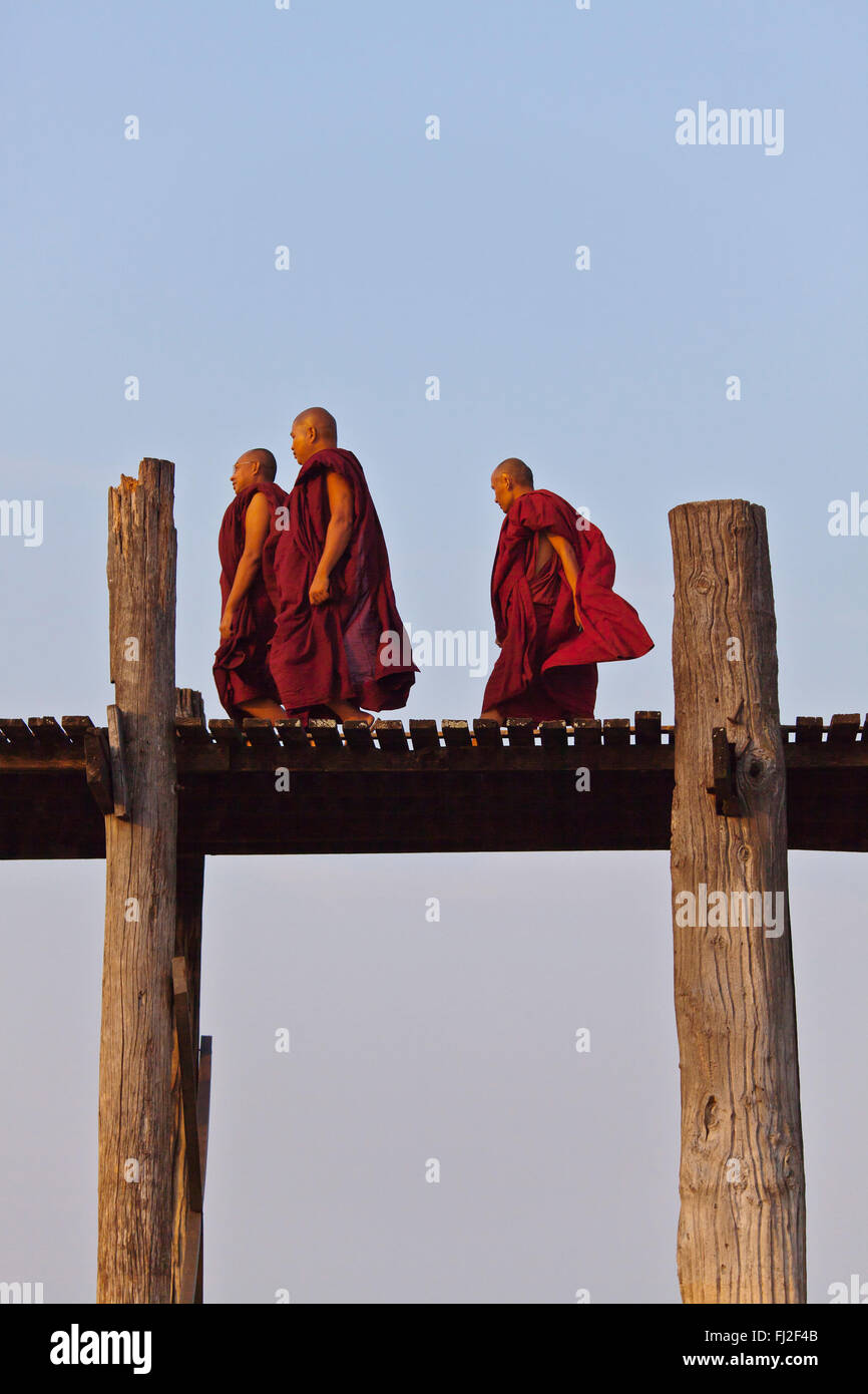 I MONACI BIRMANI utilizza il teak U BEINS ponte per commutare tra il Lago Taungthaman presso sunrise - AMARAPURA, MYANMAR Foto Stock