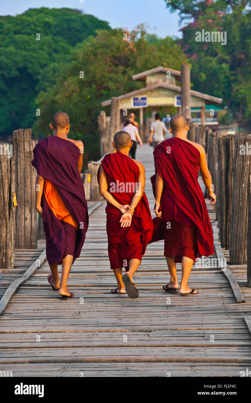 I MONACI BIRMANI utilizza il teak U BEINS ponte per commutare tra il Lago Taungthaman presso sunrise - AMARAPURA, MYANMAR Foto Stock