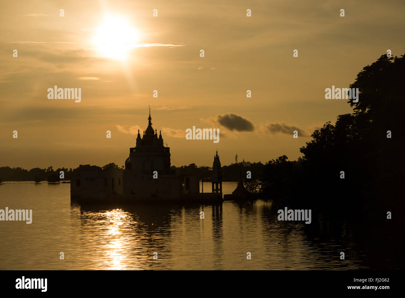 Taungthaman Lake Pagoda silhouette Mandalay Myanmar // TAUNGTHAMAN Lake, Myanmar — Una sagoma di pagoda si estende nel lago Taungthaman vicino a Mandalay, uno dei corpi idrici culturalmente più significativi del Myanmar centrale. Il lago guadagnò importanza durante la dinastia Konbaung (1752-1885) quando divenne strategicamente posizionato tra le mutevoli capitali reali del Myanmar. Situato a 11 chilometri a sud-ovest di Mandalay nella cittadina di Amarapura, questo lago stagionale si collega al sistema fluviale Ayeyarwady e ospita il famoso ponte U Bein, di 1,2 chilometri. L'area funge da centro vitale per i Buddha Foto Stock