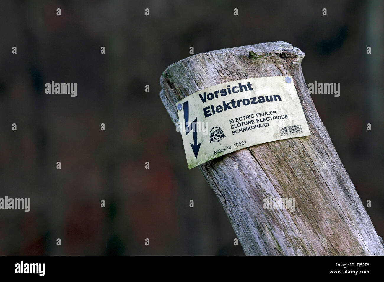 Palo di legno con segnaletica di pericolo avvertimento contro la recinzione elettrificata, Germania Foto Stock