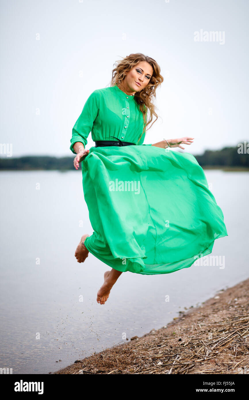 Donna felice saltando al lago Foto Stock