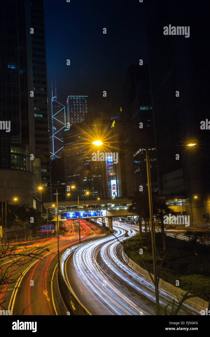 Molte tracce di auto che fillup la strada nel centro di Hong Kong. Alla fine della strada si trova il palazzo della Banca di Cina ( Hong Kong ) Foto Stock