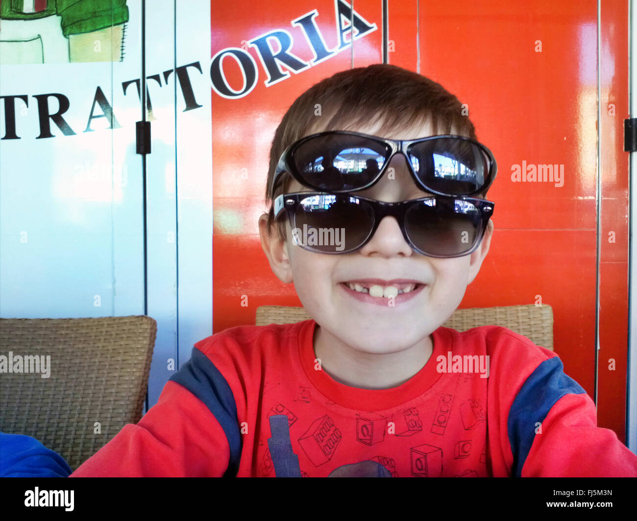 Molto cool boy con due sunglasseses in una trattoria Foto Stock
