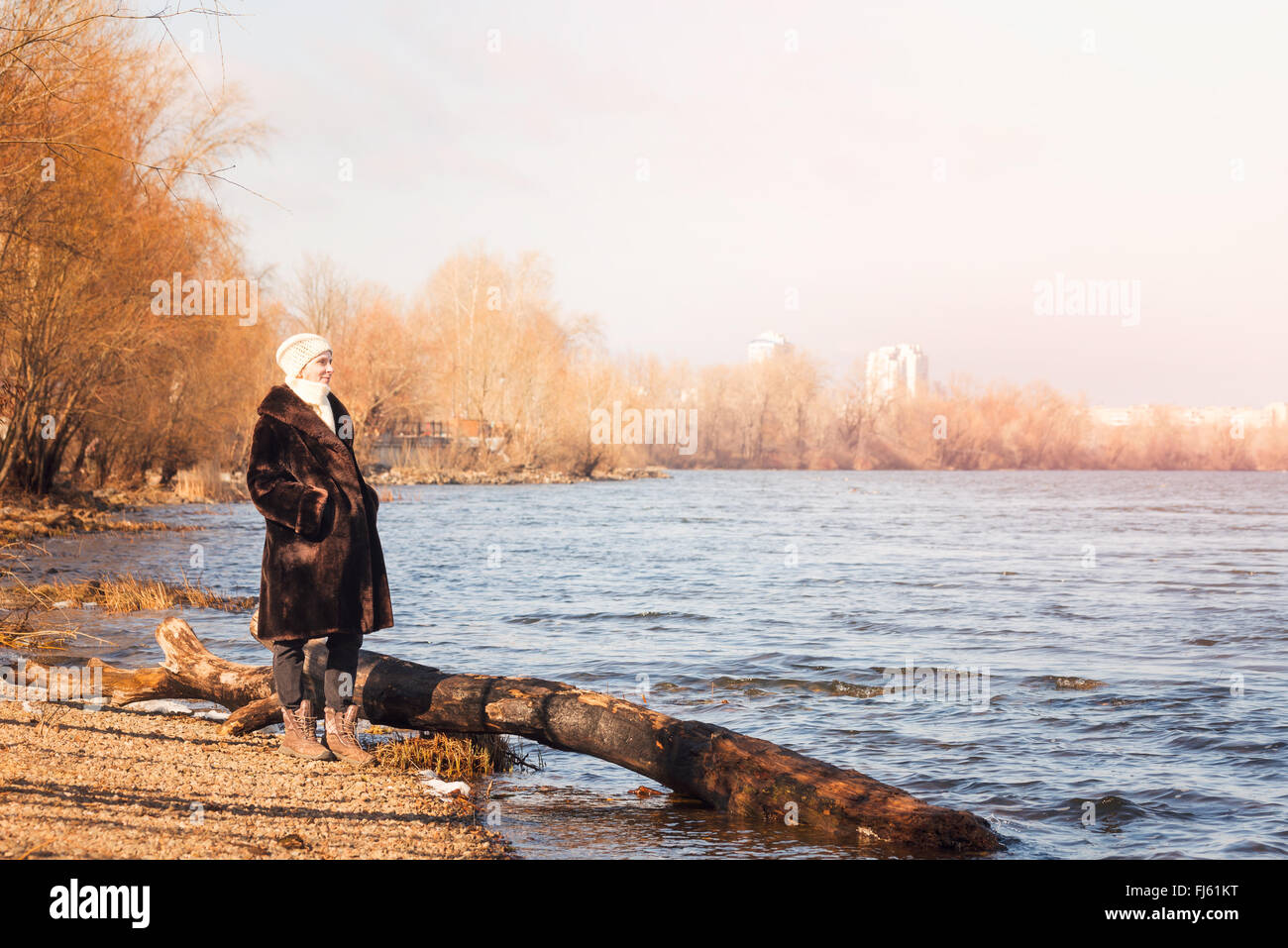 Una donna matura che indossa una calda pelliccia e un cappello di lana resta vicino al fiume Dnieper a Kiev, Ucraina, durante la stagione invernale Foto Stock