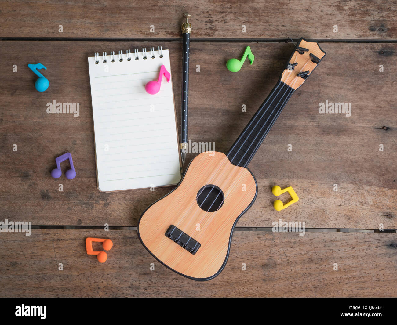 La strumento musicale - chitarra , note musicali e il notebook sul vecchio tavolo in legno Foto Stock