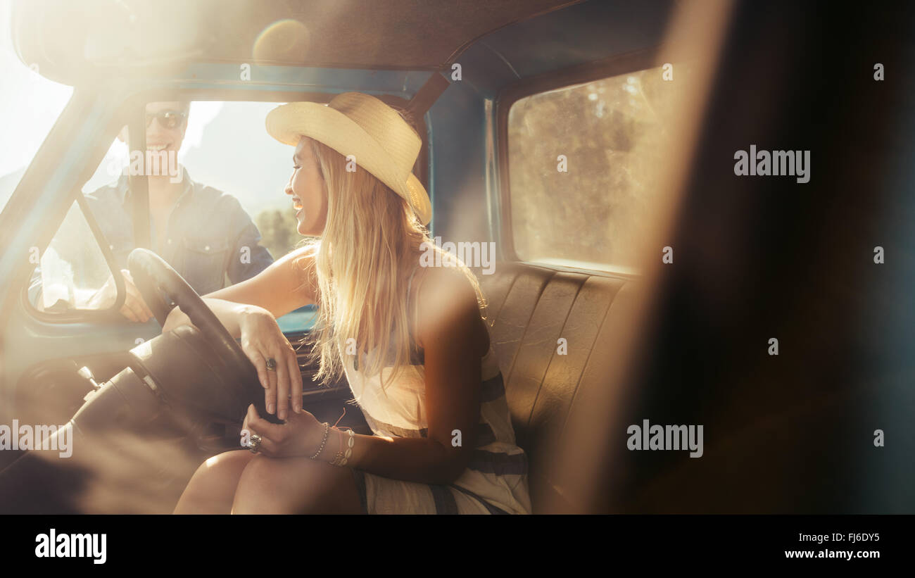 Ritratto di giovane donna seduta in una macchina a parlare con gli amici in piedi dall'auto. Foto Stock