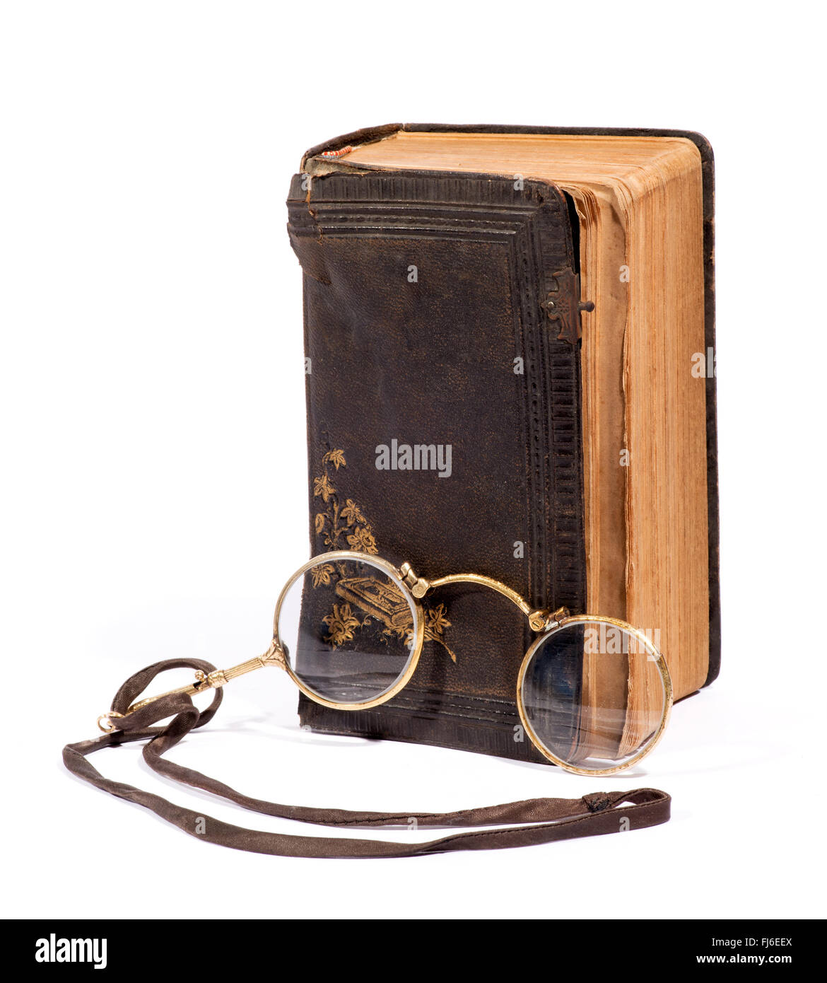 Coppia di vintage pince-nez occhiali su un laccetto per la lettura insieme con un vecchio usurato in cuoio invecchiato libro rilegato Foto Stock